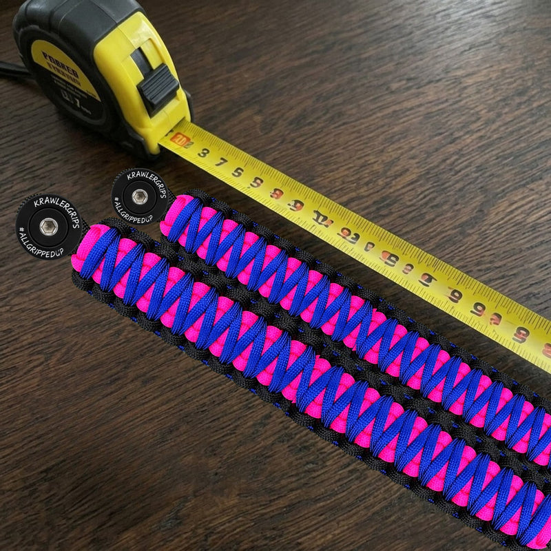 Two pink, blue and black Krawlergrips paracord grab handles with engraved black washers next to a tape measure, for custom size orders